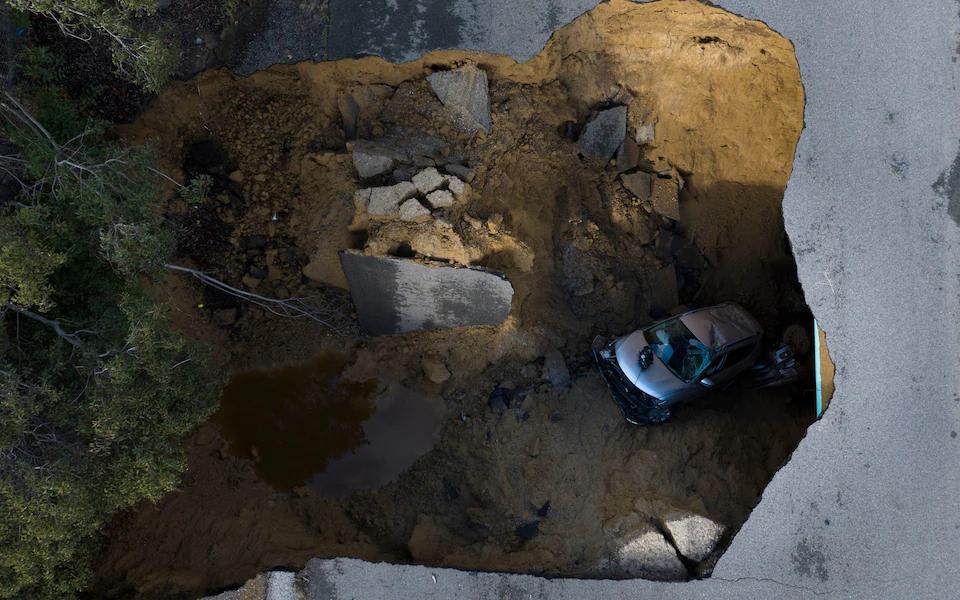 Giant sinkholes swallow cars as torrential rain batters California