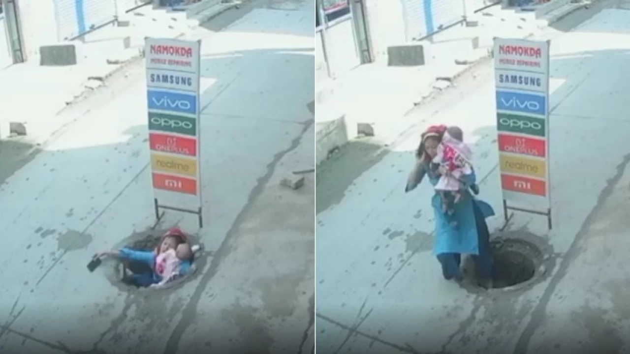 Distracted by phone, mother carrying baby falls into manhole